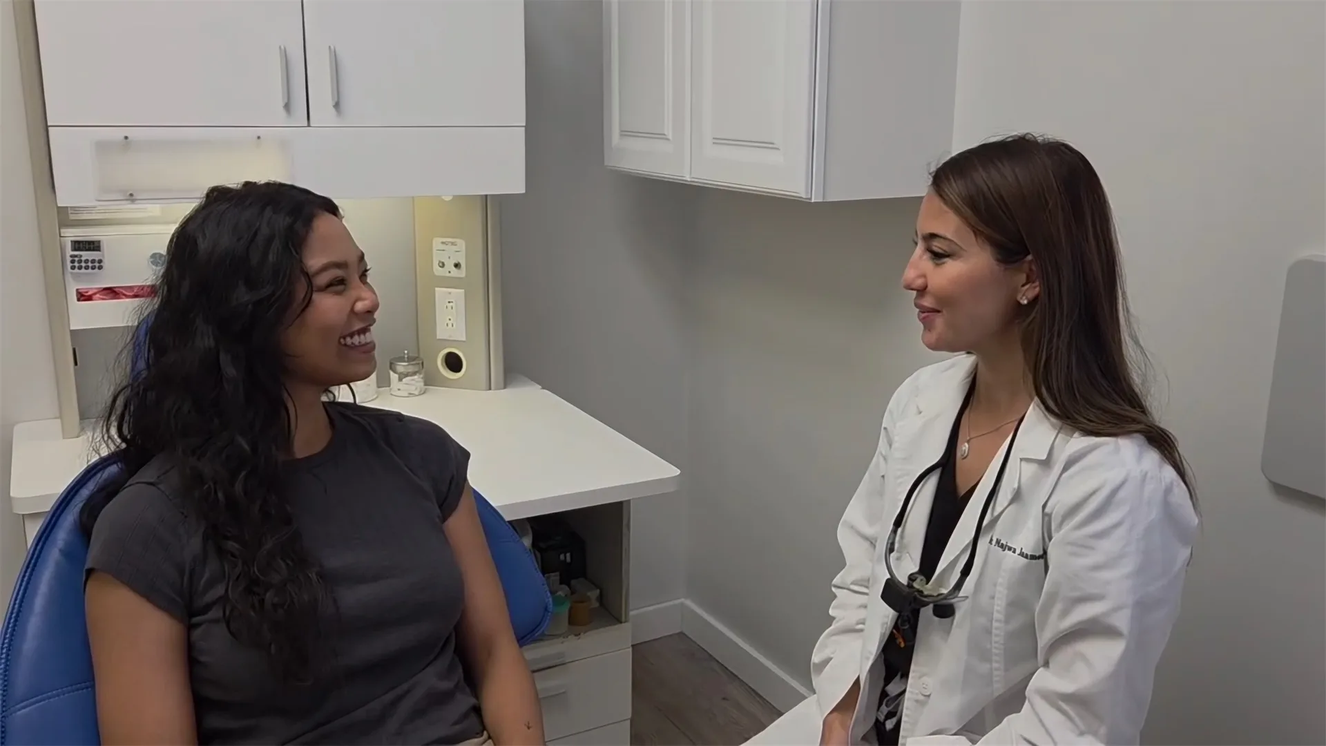 Dr. Jaamour in a white coat, smiling and talking with a woman in the dental chair at Pearl Dental Care in Westmont